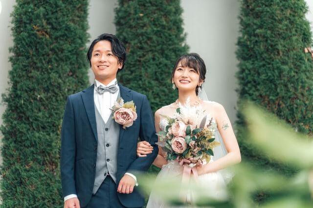 ネイビーのタキシードにシルバーの蝶ネクタイとベストを合わせた新郎とウエディングドレス姿の新婦。