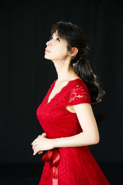 赤いドレスを着てステージに立つ女性